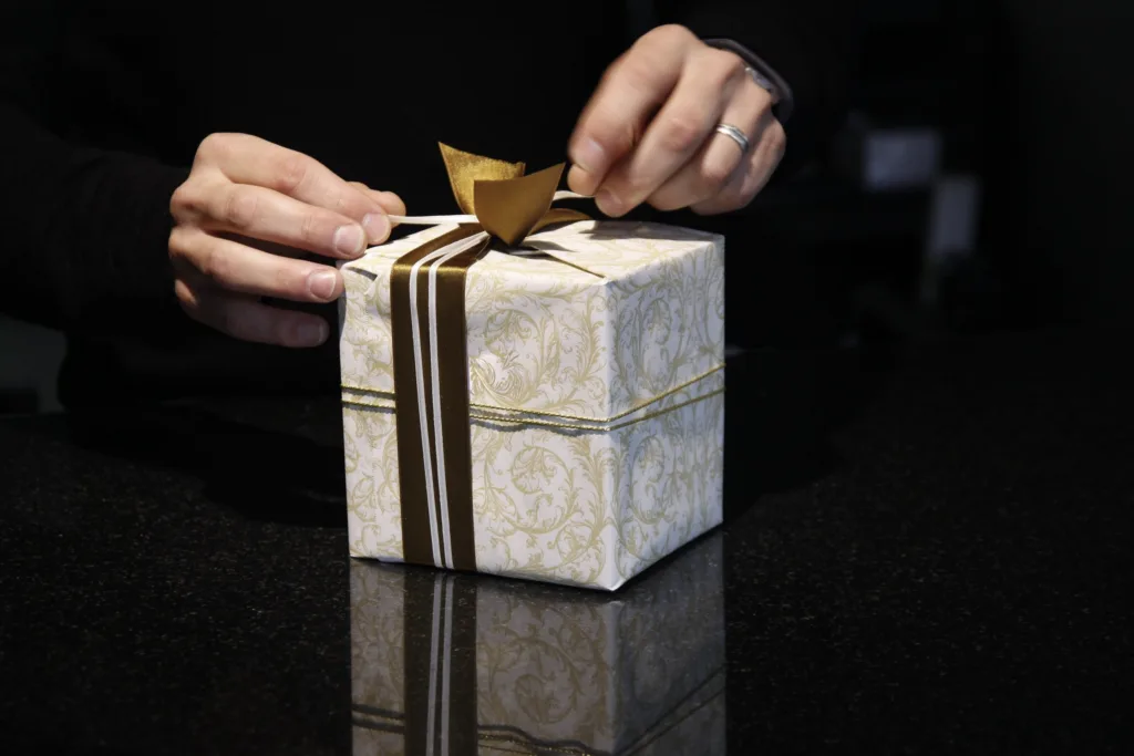 hands tie a bow on a small gift