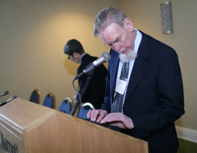 photo of Gil Johnson standing at a lectern.