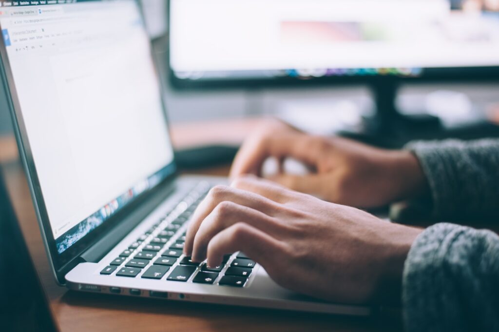 Two hands typing on a laptop