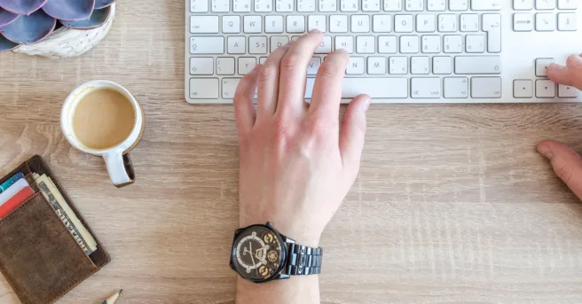 Desk with a keyboard, wallet, notebook, pencil, and coffee, symbolizing organizing finances and daily tasks.