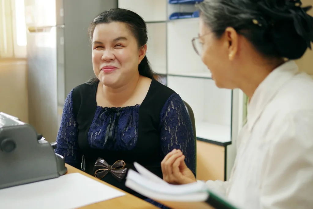 Woman smiling during a conversation with another person in an office setting.