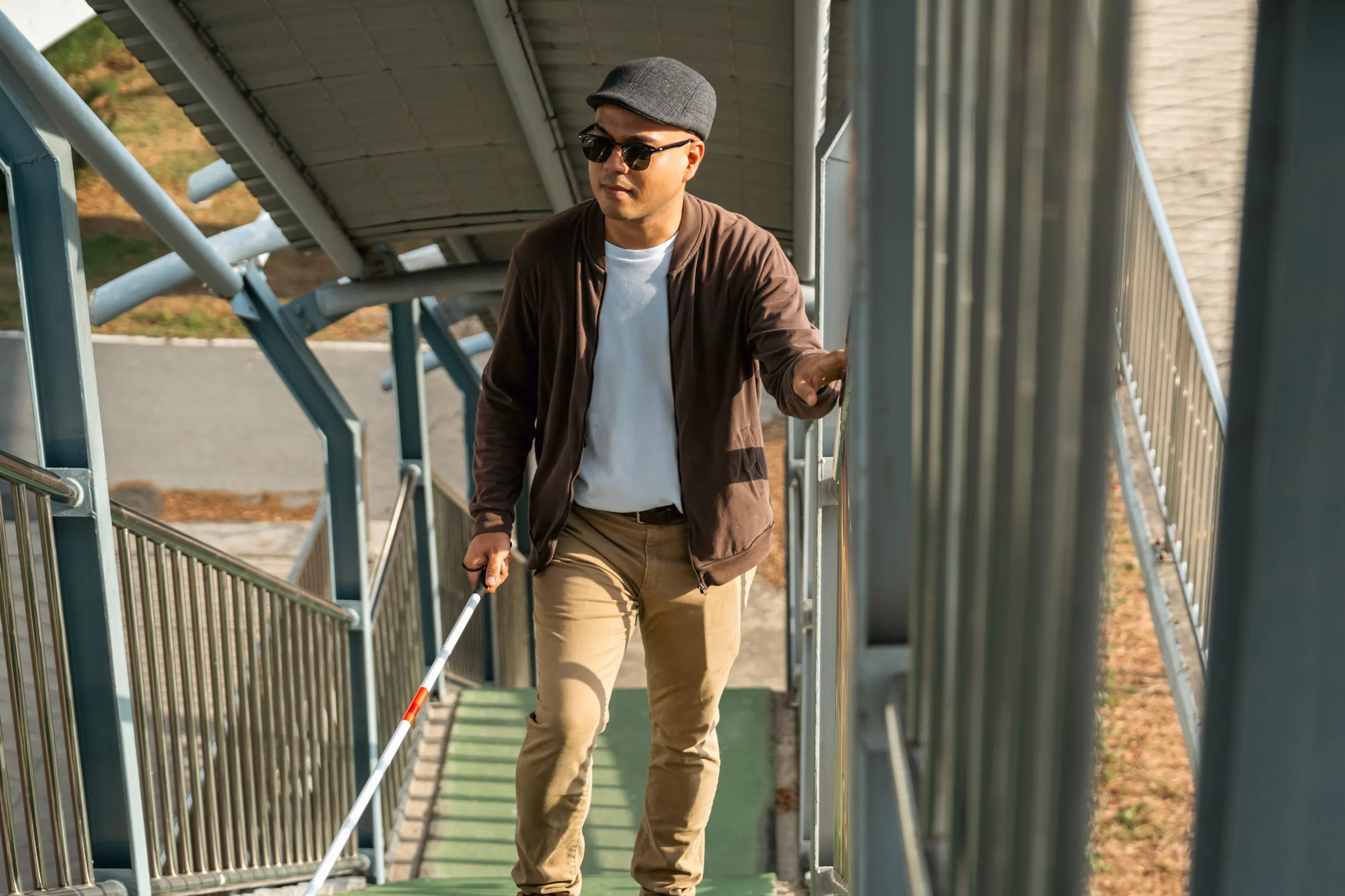 Man with white cane walking upstairs on train platform