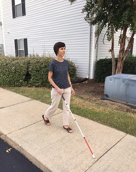 Person walking confidently with a white cane.