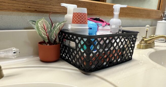 A bathroom counter with a basket of toiletry items.