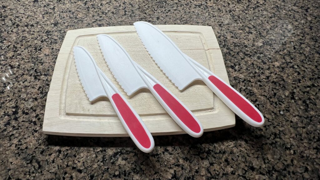 A cutting board with three different size beginning knife set.