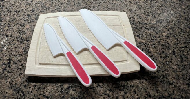A cutting board with three different size beginning knife set.