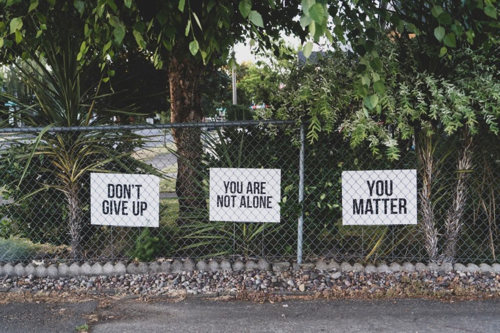 signs on fence saying: "Don't give up" "You are not alone" "you matter"