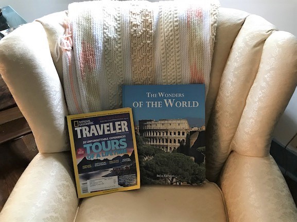 armchair with two travel books: The Wonders of the World and National Geographic Traveler Tours