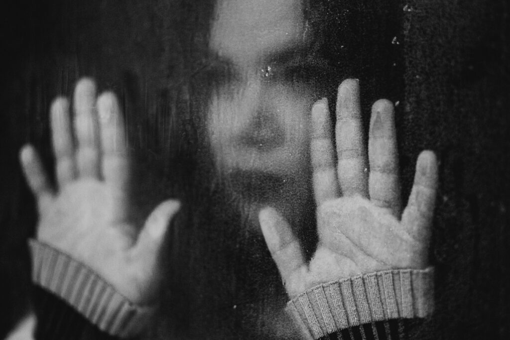 black and white photo of woman looking sad and holding out her hands in front of her face