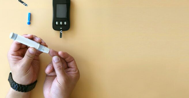 closeup of glucose monitor and person sticking finger