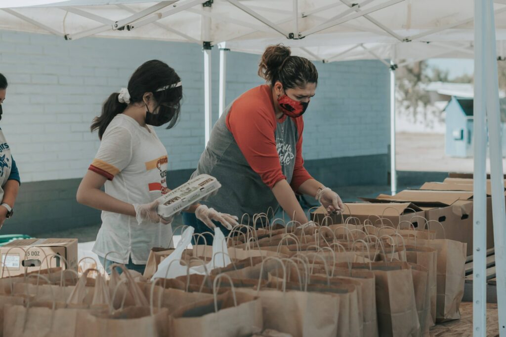 Two people filling food bags at a volunteer center.