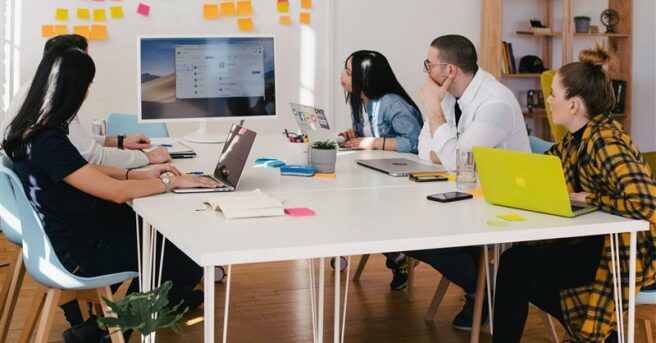 group of employees sit at a conference table for a presentation