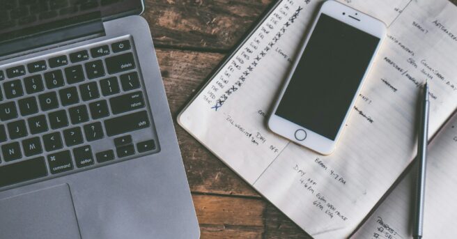 desk with a laptop, iPhone, and calendar