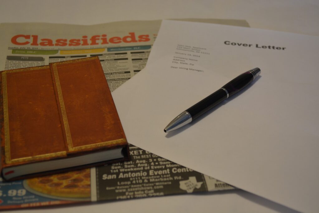 Photo of newspaper, notebook, pen and cover letter