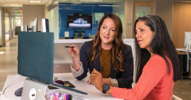 Two people in business wear talk in a professional setting