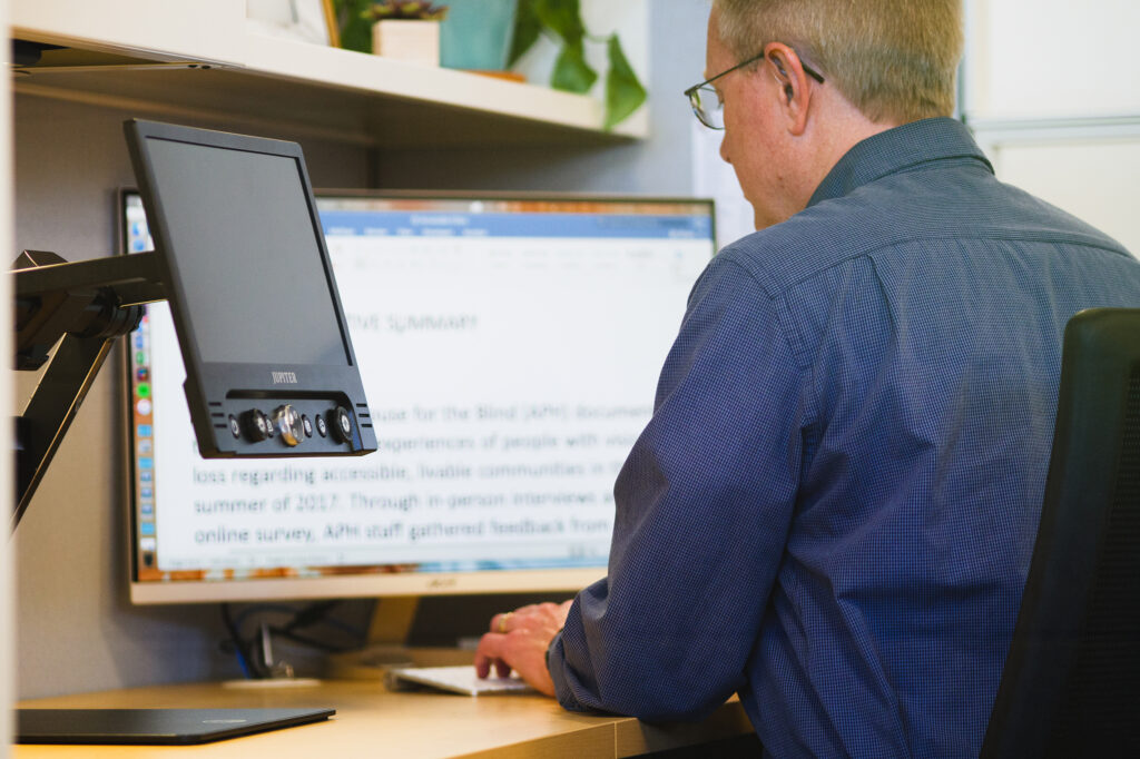 Man sitting at computer with magnifier