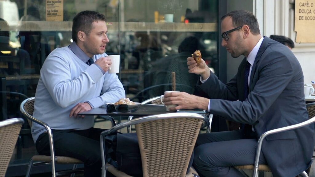 Two men meeting for coffee outside a business