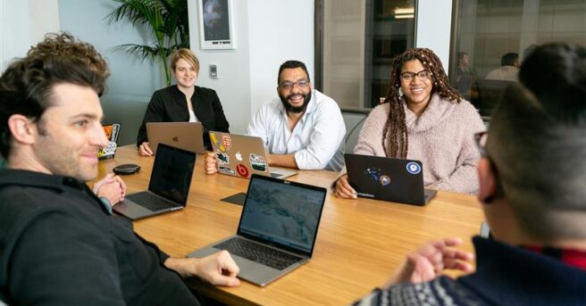 diverse coworkers sit around a large table for a meeting
