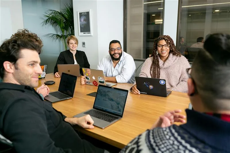 diverse coworkers sit around a large table for a meeting
