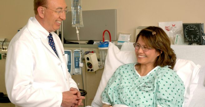 patient with eyeglasses smiling in a hospital bed near doctor