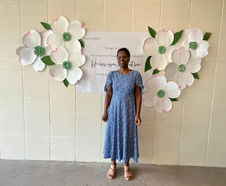 Author standing in front of a wall with large flowers
