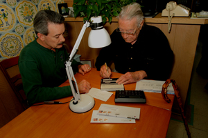 Older man setting at table with son writing checks