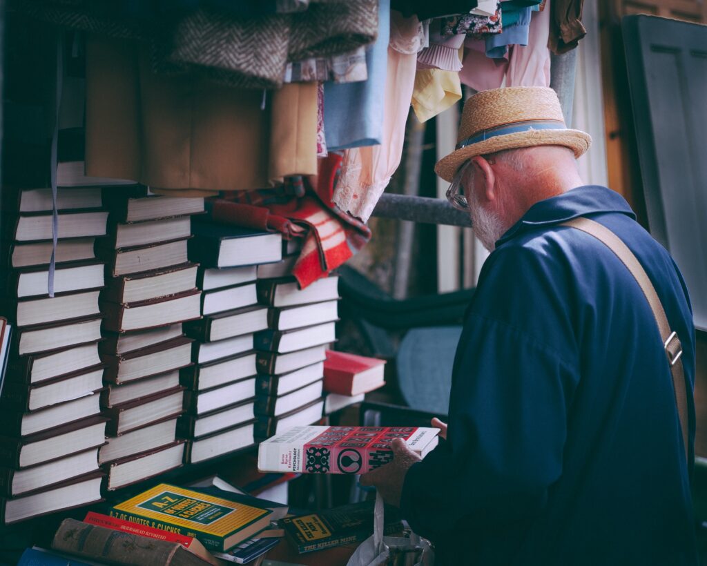 Photo of a man wearing glasses sorting through used books