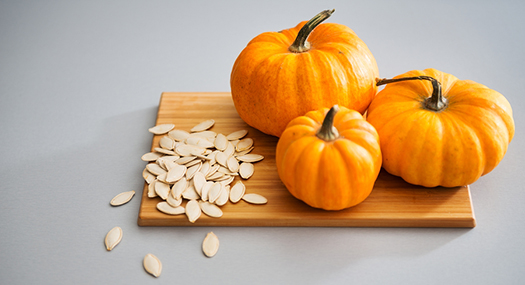 three mini pumpkins and seeds on a cutting board