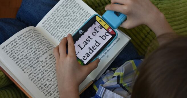 Child using a video magnifier reading a book.