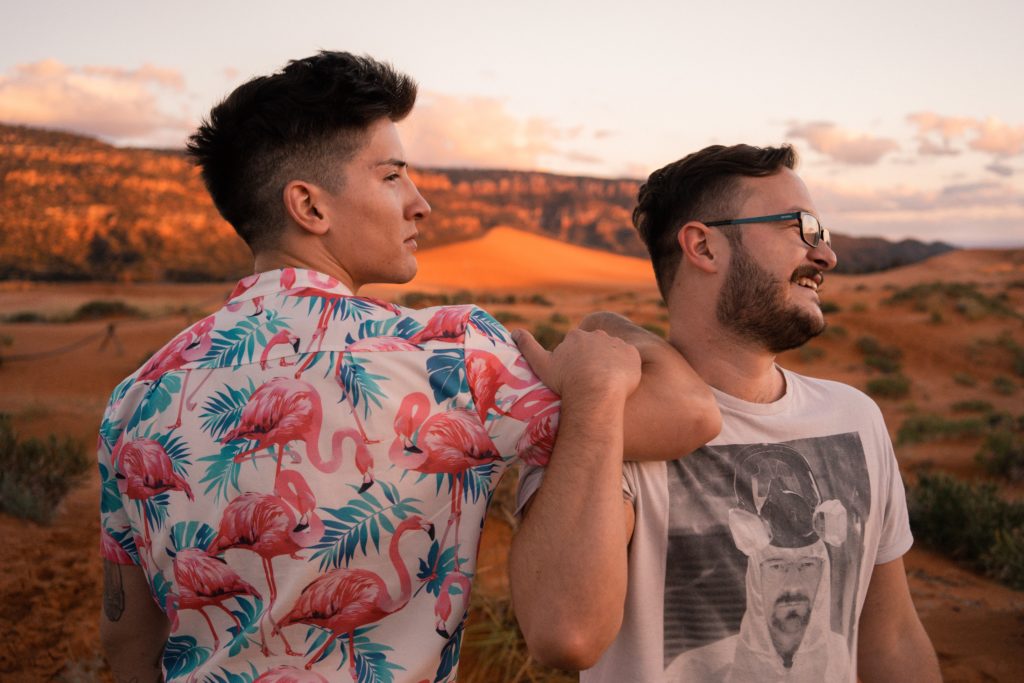 Two men sitting together one with his arm on the shoulder of the other.