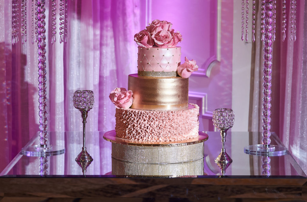 3 tier cake with pink flowers. pink ruffle icing and pearls for sparkle