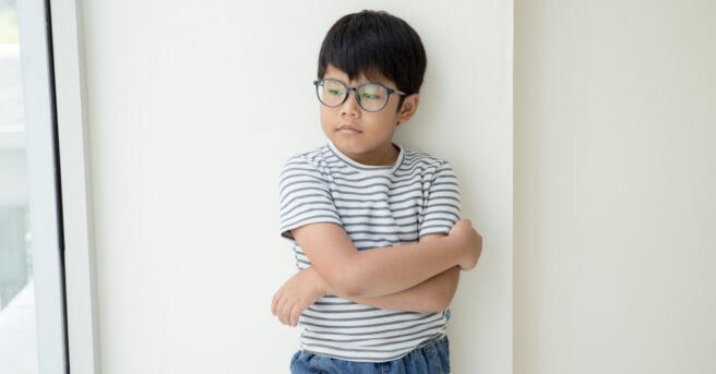 Kid in white stripped t-shirt and glasses with crossed arm across his chest.