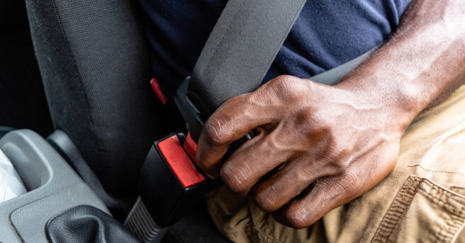 Close-up of a person buckling a seatbelt