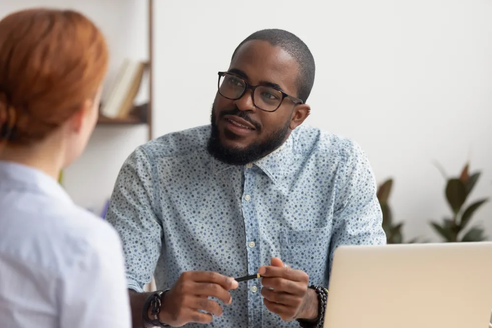 Man sitting at desk interviewing a person