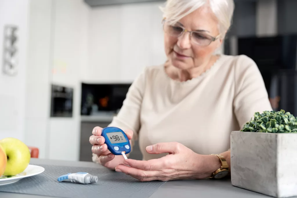 Senior woman with glucometer checking blood sugar level at home.