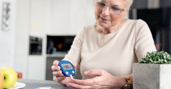 Senior woman with glucometer checking blood sugar level at home.