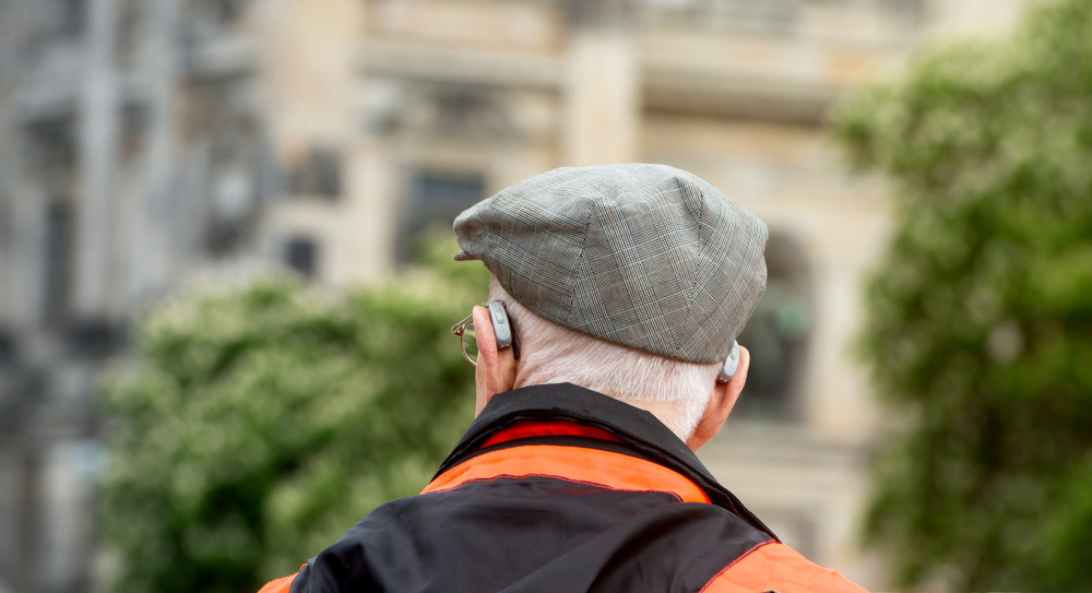 Individual wearing hearing aids walks outdoors