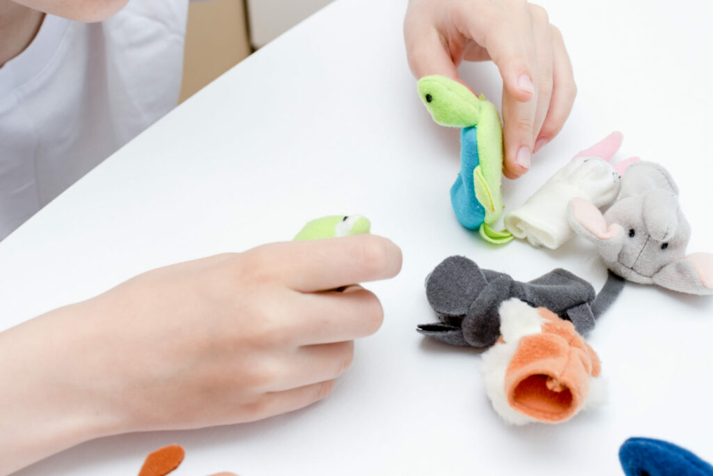 A child playing with various finger puppets.