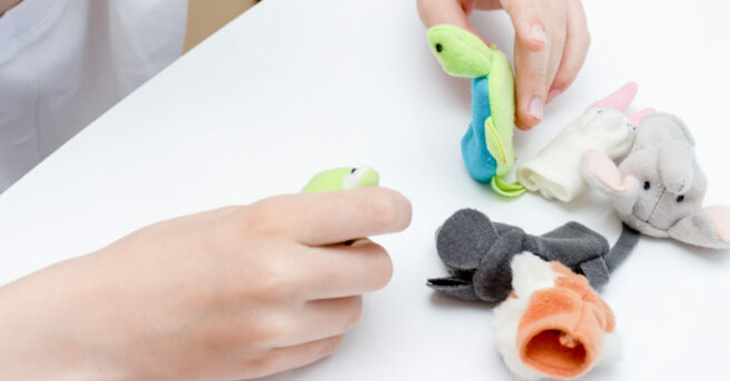 A child playing with various finger puppets.