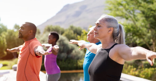 Group of diverse people practicing yoga outdoors