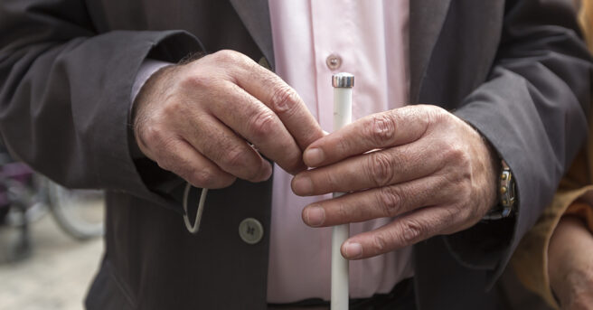 Close-up of hands holding a white cane