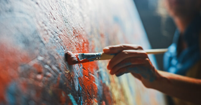 Close-up of person painting a vibrant, abstract painting