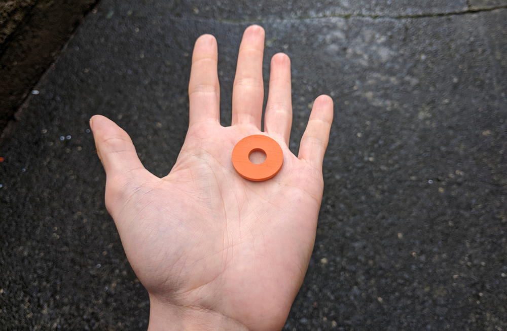 person holds a rubber washer, a quarter size circle