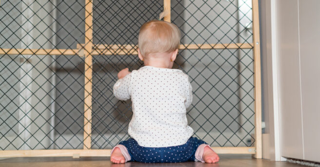 Baby playing behind safety gate.