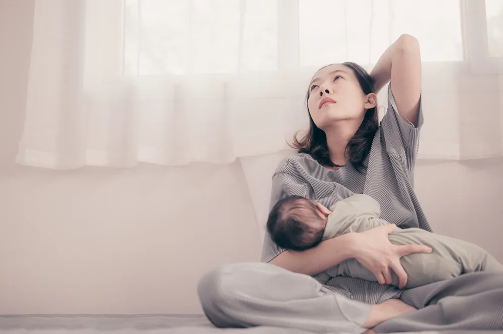 Mom holding her baby feeling overwhelmed.