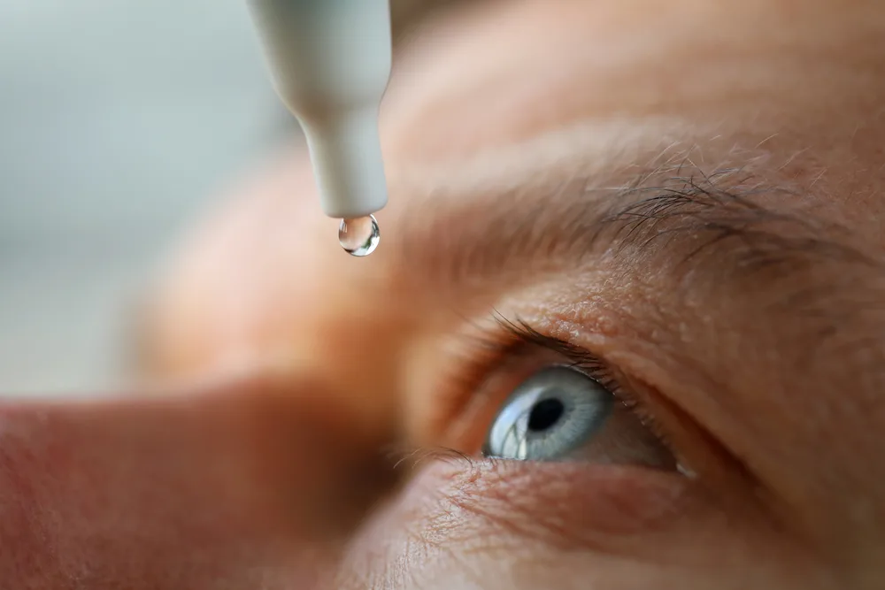 Person putting eye drops in their eye