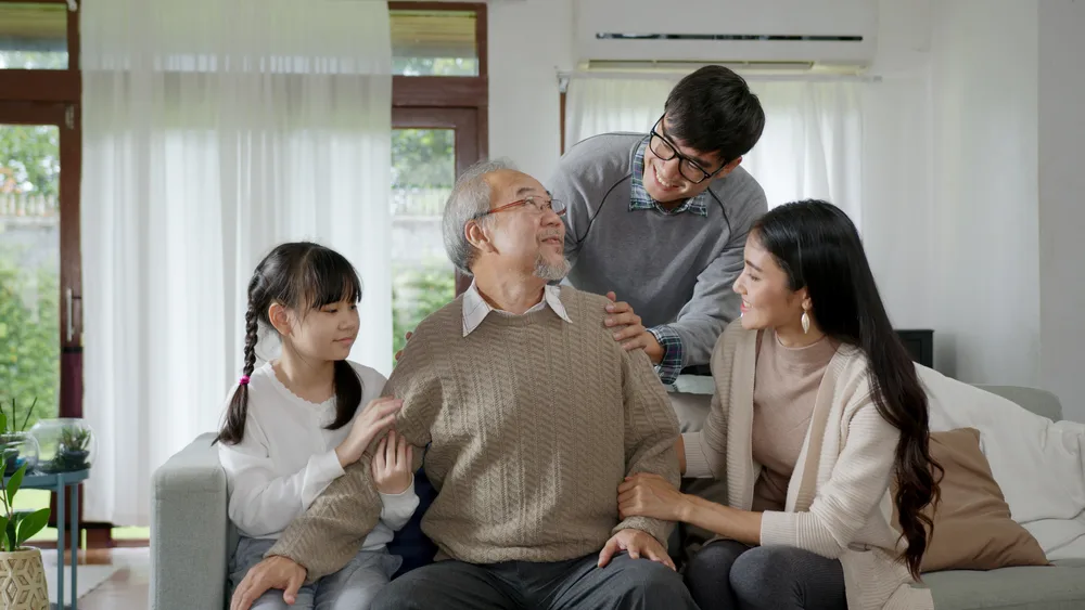 Older man wearing eyeglasses surrounded by family of various ages