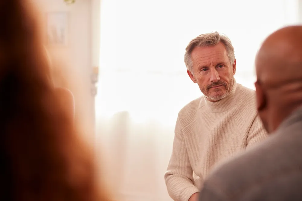 Older person sitting next to others