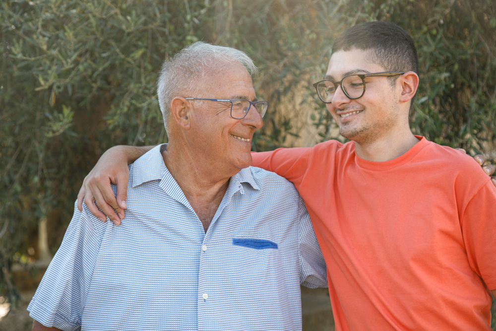 Older person and young teen put their arms around each other