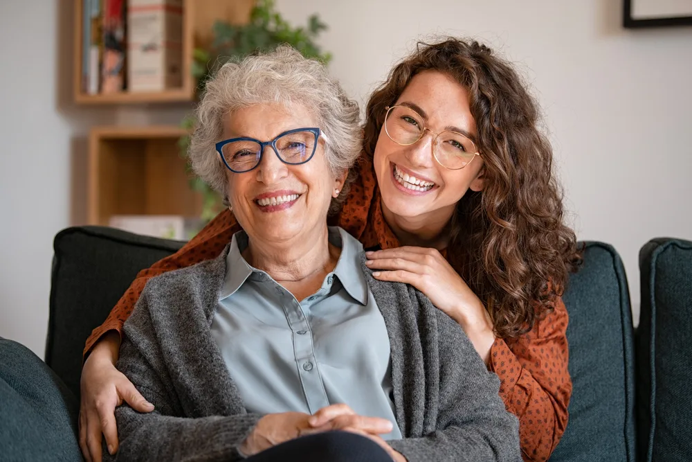 older person smiling and a younger person embracing them